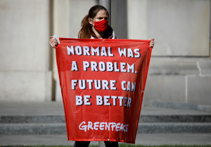 A Greenpeace protester holds a banner saying Normal was a problem. Future can be better